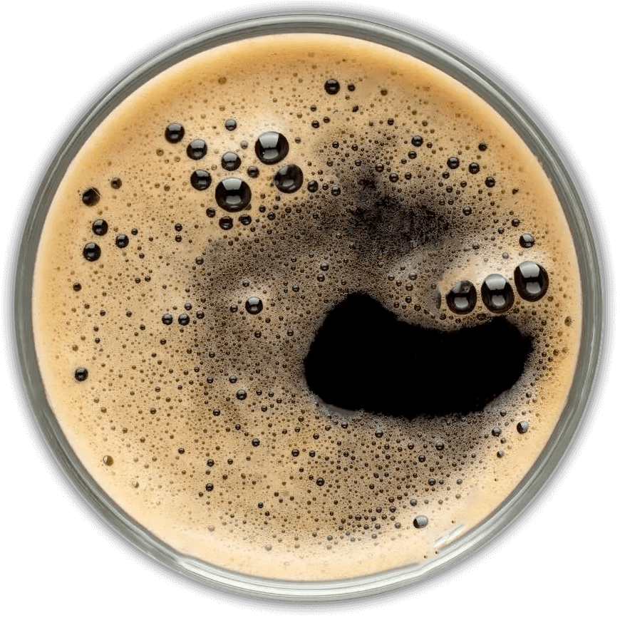 Overhead view of glass of dark beer. The surface is foamy with small bubbles.