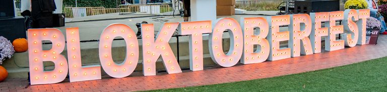 Giant marquee letters spelling BLOKTOBERFEST with orange bulbs.